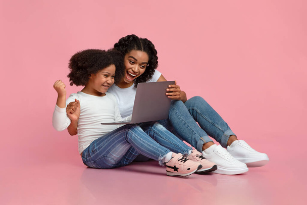 Cieszyła się czarną mamą i małą córeczką świętującą sukces z laptopem - Zdjęcie, obraz