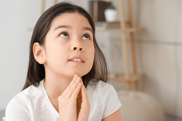 Söpö pieni aasialainen tyttö rukoilee kotona
 - Valokuva, kuva