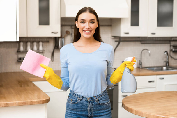 Uśmiechnięta kobieta stojąca w kuchni z detekcyjnym sprayem - Zdjęcie, obraz