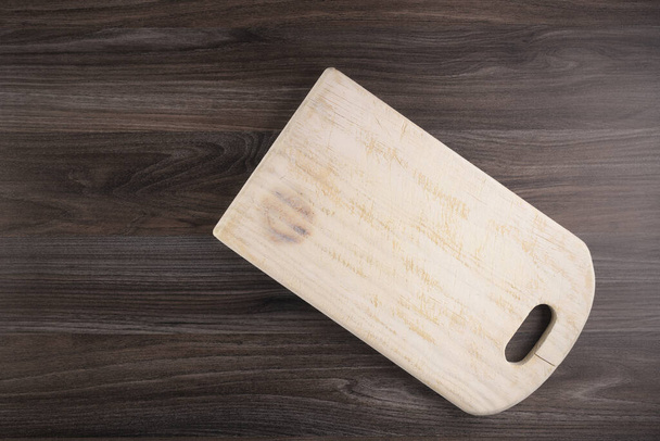 Top view of wooden cutting board on old dark wood countertop. - Fotoğraf, Görsel