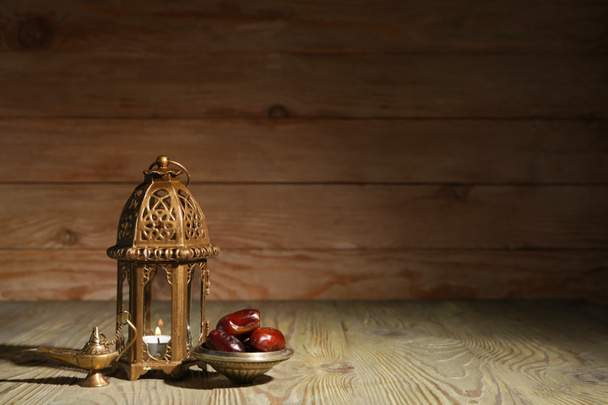 木製の背景にイスラム教徒のランプと日付 - 写真・画像