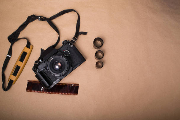 Retro fényképezőgép fénykép film és keret fotó kártya barna papír háttér. Szüreti fotó fotótechnológiával felülnézetből - Fotó, kép