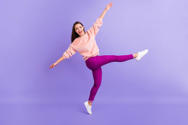 Full size profile photo of funny lady rejoicing spend lovely time dancing youth party raise arms leg wear casual fur fuzzy sweater pants sneakers isolated purple color background - Фото, зображення