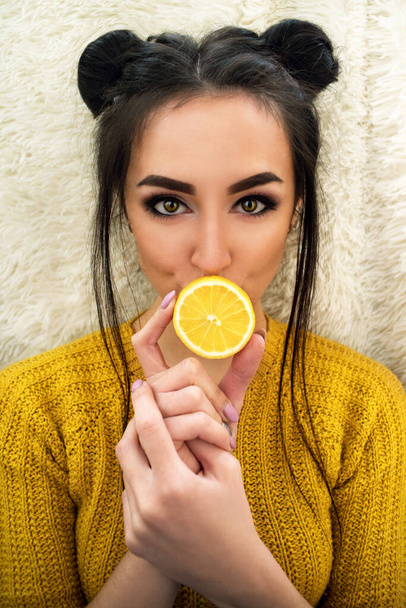 Muotokuva nuoresta tytöstä, jolla on sitruuna. Trendikäs ilme tyttö sitrushedelmien lähellä hänen kasvonsa
 - Valokuva, kuva