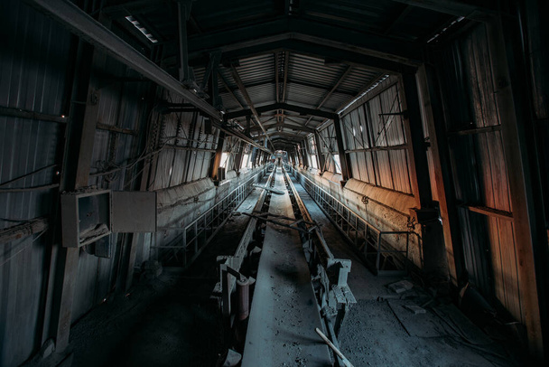 Abandoned cement and concrete factory. Old rusty conveyor in corridor - Zdjęcie, obraz