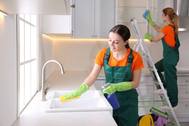 Zespół profesjonalnych woźnych sprzątających nowoczesną kuchnię - Zdjęcie, obraz