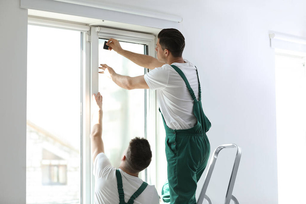 Professional workers tinting window with foil indoors - Photo, Image