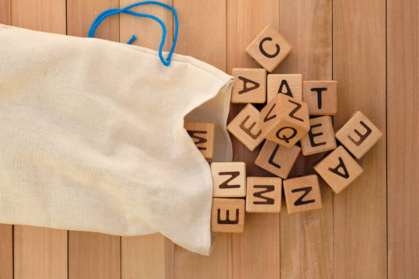 Stofftasche und Holzwürfel von oben. Holzwürfel mit Buchstaben des englischen Alphabets, Lernspiele für Kinder. Leinentaschen zur Aufbewahrung von Spielzeug und Geschenkverpackungen. - Foto, Bild