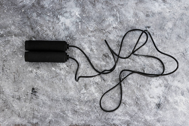 fitness and home gym gear concept, skipping rope for intense cardio workouts on concrete background - Foto, afbeelding