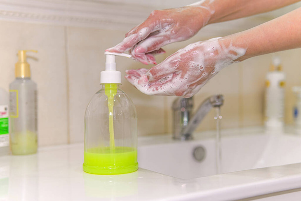 Pese kädet saippualla hanan alla vedellä uutta koronavirusta vastaan. Antiseptinen, hygienia, terveydenhuollon käsite. nainen pesee kätensä nestemäisellä saippualla pullosta. COVID-19 Hygienia-käsite
. - Valokuva, kuva