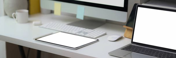 Oříznutý záběr kancelářského stolu s prázdnou obrazovkou notebooku, tabletu a počítače na bílém stole v moderní domácí kanceláři  - Fotografie, Obrázek
