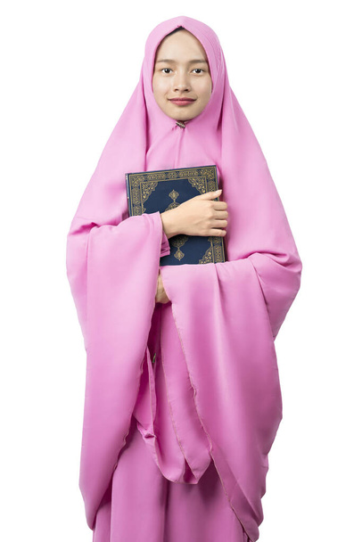 Asian Muslim woman in a veil standing and holding the Quran isolated over white background - Valokuva, kuva