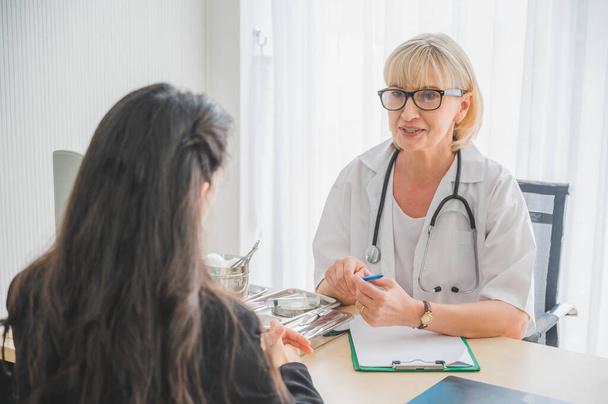Senior female doctor meet the patient discussing and making notes about symptom problem. Health care and client service in medicine concept. - Foto, Imagem