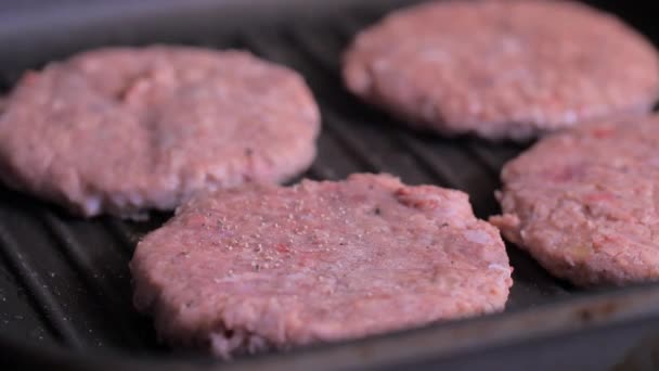 Sprinkle ground pepper on the meat for burgers on the black pan. - Séquence, vidéo