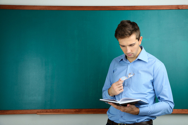 Young teacher near chalkboard in school classroom - Foto, Bild