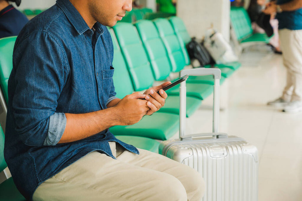 Viaggiatori con trolley bag Utilizzando uno smartphone per comunicare Lui è in aeroporto
. - Foto, immagini