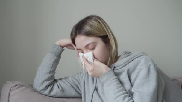 Close-up. The blonde girl with short hair is sick, sneezes and wraps herself in a blanket from the temperature. Symptom of Orvi, coronovirus, flu, acute respiratory disease, allergy, sinusitis. - Záběry, video