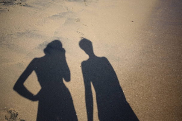 Kaksi varjoa tyttöjä hiekalla
 - Valokuva, kuva