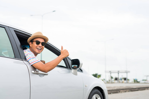 Молодий азіатський чоловік показує великий палець під час водіння машини
. - Фото, зображення