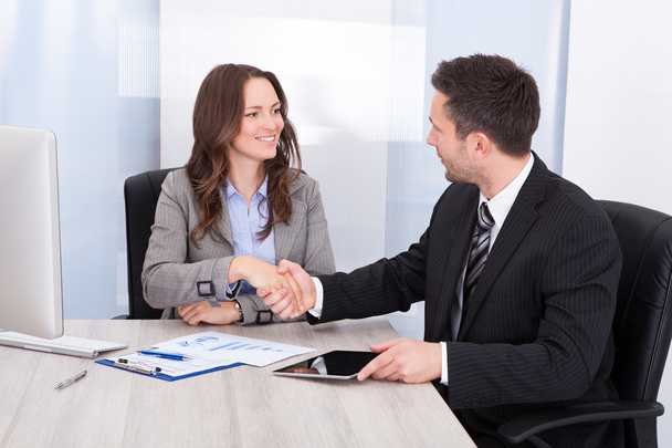 Looking At Businessman While Shaking Hand At Office Desk - Photo, Image