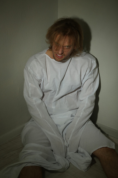 Mentally ill man in strait-jacket in room corner - Foto, Imagen