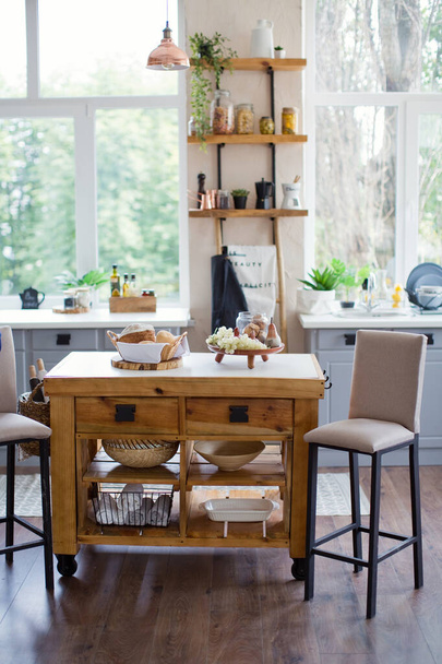 Φωτεινό εσωτερικό κουζίνας με ξύλινες λεπτομέρειες και μεγάλα παράθυρα - Φωτογραφία, εικόνα