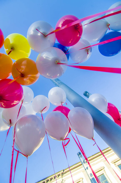 μπαλόνια όλων των χρωμάτων πετούν στον γαλάζιο ουρανό προς τέρψη των παιδιών - Φωτογραφία, εικόνα