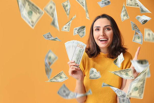Schöne junge Frau mit fliegendem Geld auf farbigem Hintergrund - Foto, Bild