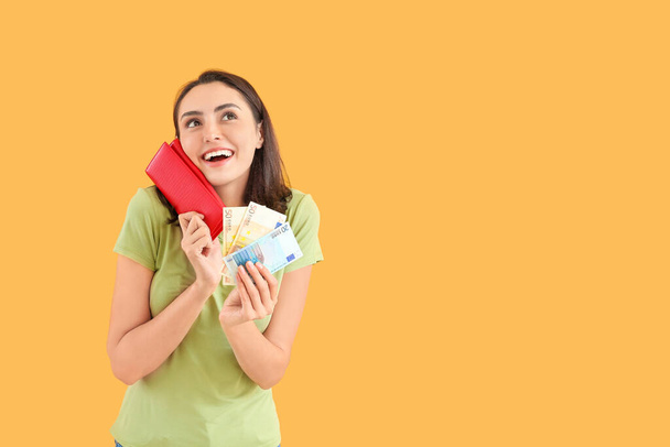 Young woman with wallet and money on color background - Φωτογραφία, εικόνα