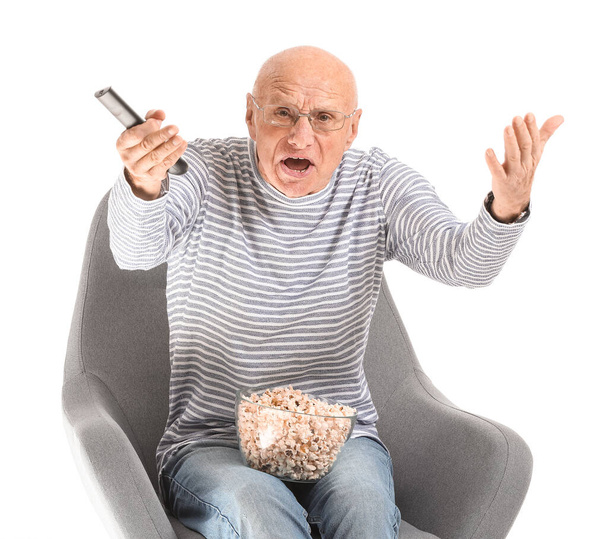Portrait of displeased elderly man watching TV on white background - Photo, Image