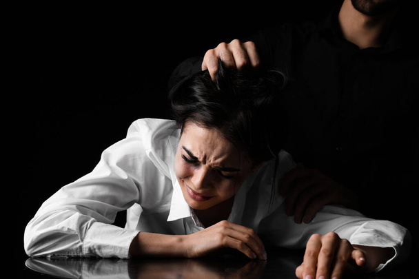 Angry husband trying to kill his wife on dark background. Concept of domestic violence - Foto, imagen
