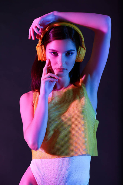 Toned portret pięknej młodej kobiety ze słuchawkami na ciemnym tle - Zdjęcie, obraz