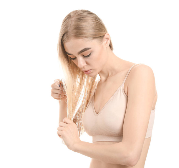 Young woman combing her hair against white background - Fotoğraf, Görsel