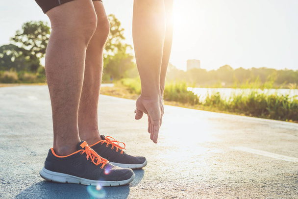 Erkek spor sağlık konsepti: parktaki yolda koşan spor ayakkabılı koşucu ayaklarını kapat. Ayakkabıya odaklan. Metin veya tasarım için fotokopi alanı ile sabah saatinde, güneş ışığında ve sıcak efektlerle çekilen - Fotoğraf, Görsel