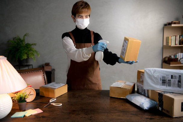 Osoba spryskująca paczki i skrzynki środkiem dezynfekującym podczas pandemii Covid-19 - Zdjęcie, obraz