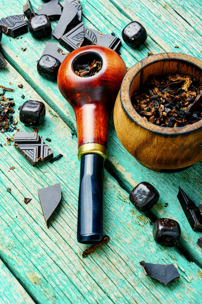 Chocolate flavored tobacco for smoking pipes.Tobacco pipe filled with tobacco.Smoking pipe on wooden table - Photo, Image