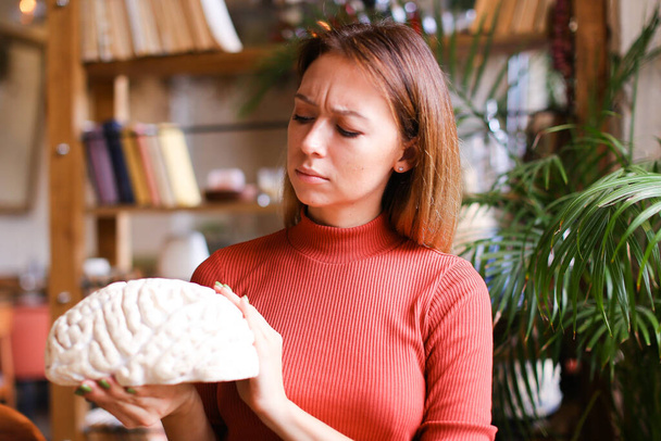 Mujer psiquiatra reflexiva sosteniendo modelo de cerebro humano en el gabinete
. - Foto, Imagen