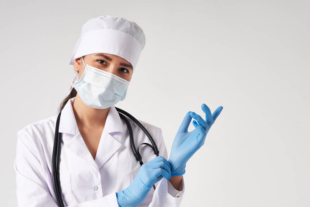 Young doctor putting on surgical gloves over white background - Zdjęcie, obraz