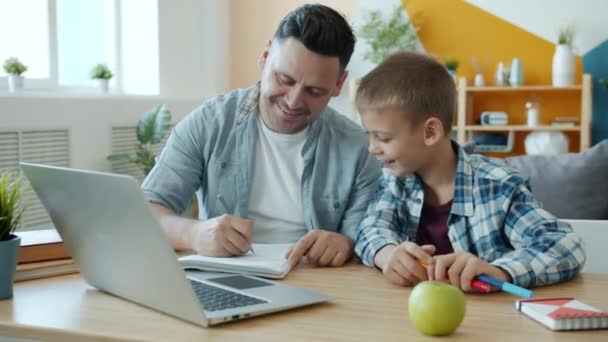Young adult man drawing in notebook having fun with happy child at home - Imágenes, Vídeo