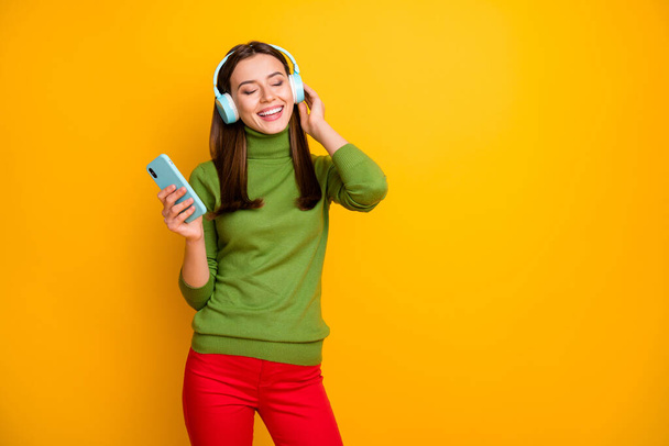 Portrait of positive cheerful girl rest relax listen music headset enjoy stereo sound radio melody wear stylish clothes isolated over vibrant color background - Фото, зображення