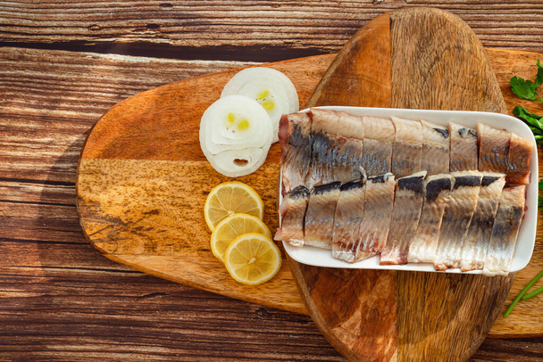 sliced salted herring on plate onion rings  lemon - Φωτογραφία, εικόνα