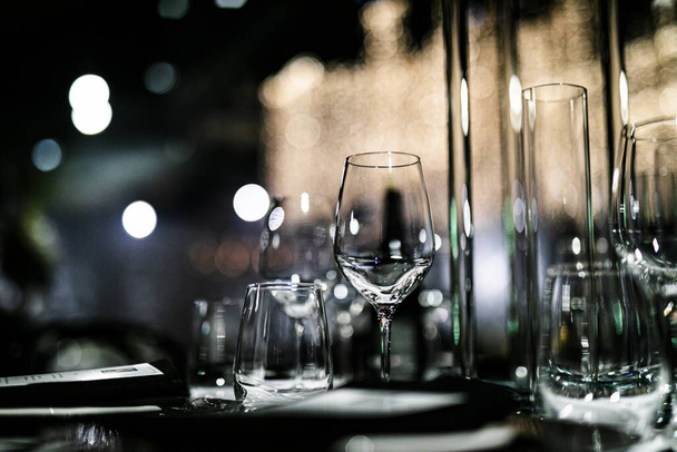 Розкішні набори столів для вишуканої їдальні зі скляним посудом, красивий розмитий фон. Для подій, весіль. реквізит на весілля, дні народження та святкування. Весілля, ресторан
, - Фото, зображення