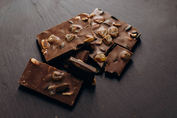 Morceaux de chocolat aux fruits secs sur une plaque de graphite noir
 - Photo, image
