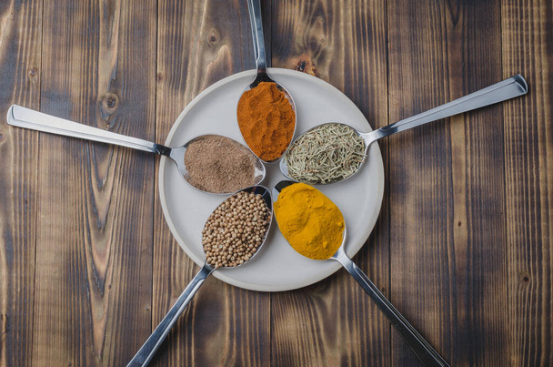 Set of various aromatic colorful spices in spoons on a in a bowl on a wooden table. Top view - Fotoğraf, Görsel
