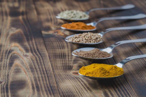various spices in spoons on a wooden table, copyspace - Fotó, kép