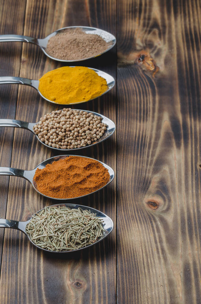 various spices in spoons on a wooden table, top view and copyspace - Photo, image