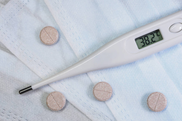 Електронний термометр і таблетки з медичною маскою
  - Фото, зображення