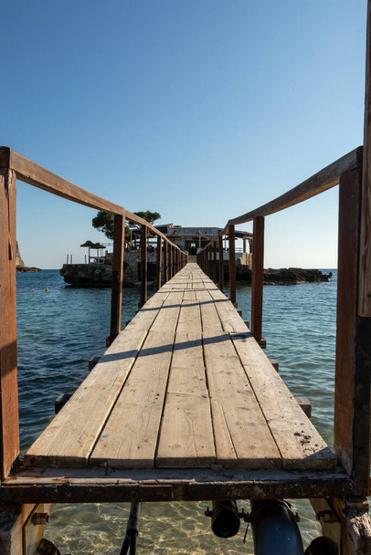 Puente de madera que lleva al otro lado del mar a una isla con un restaurante en el campamento de mar, mallorca, aflicción. - Foto, Imagen