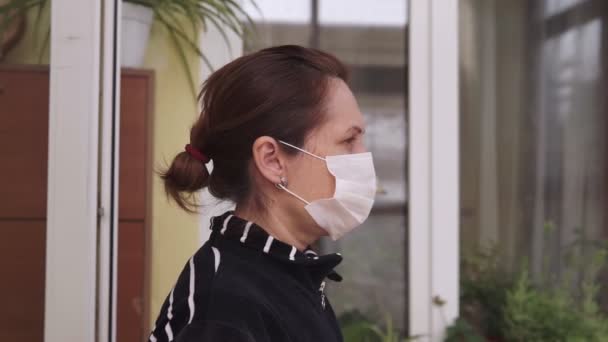 Porträt einer brünetten Frau, die sich während der Quarantäne des Coronavirus COVID-19 eine medizinische Maske über das Gesicht zieht. Epidemie, Lungenentzündung, Hygiene. Pandemie. Nahaufnahme - Filmmaterial, Video