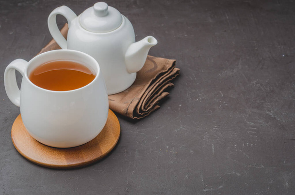 white cup of tea and teapot on a black stone background, copyspace - Foto, Imagem